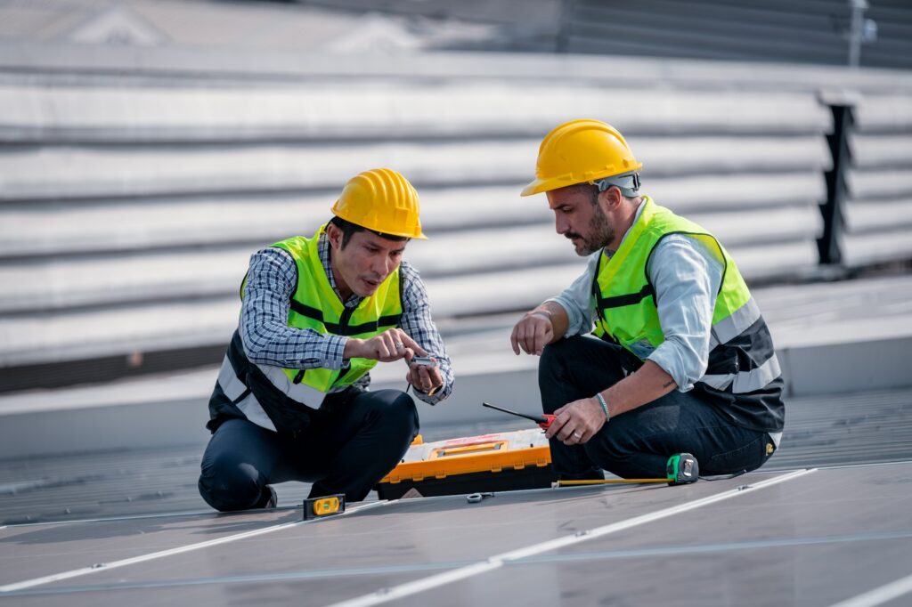 Engineers walking on roof inspect and check solar cell panel by hold equipment box and radio communi