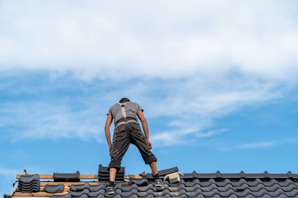 workman on the roof of a family house, building a roof covering from ceramic tiles